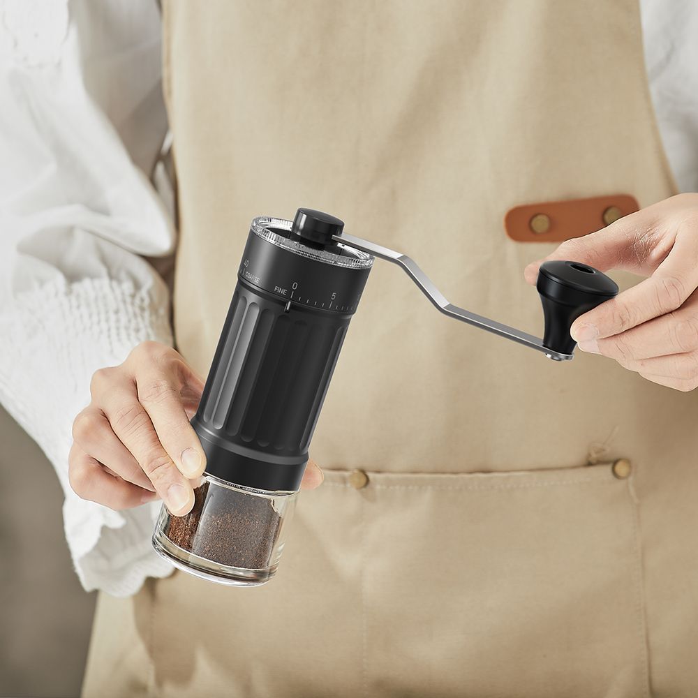 Two hands turning the crank of the Ermona hand grinder.